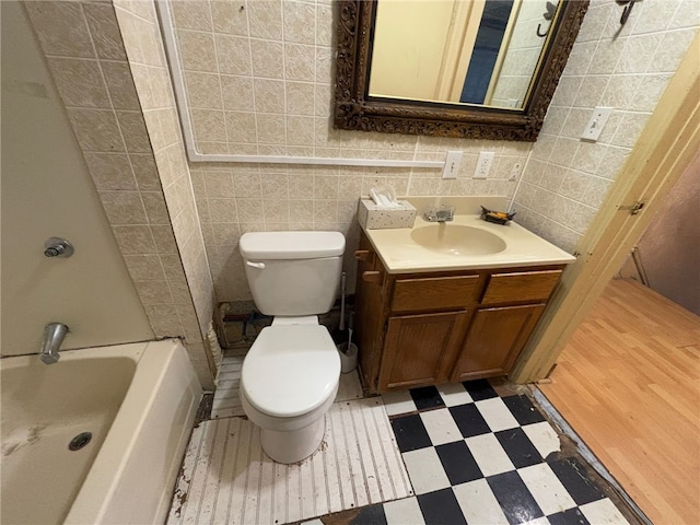 bathroom with vanity, toilet, and tile walls