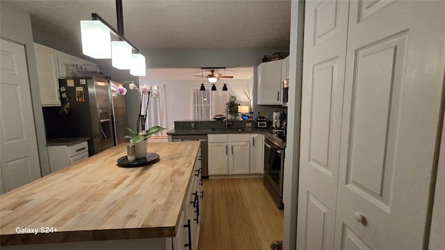 kitchen with sink, white cabinetry, wooden counters, hanging light fixtures, and stainless steel appliances