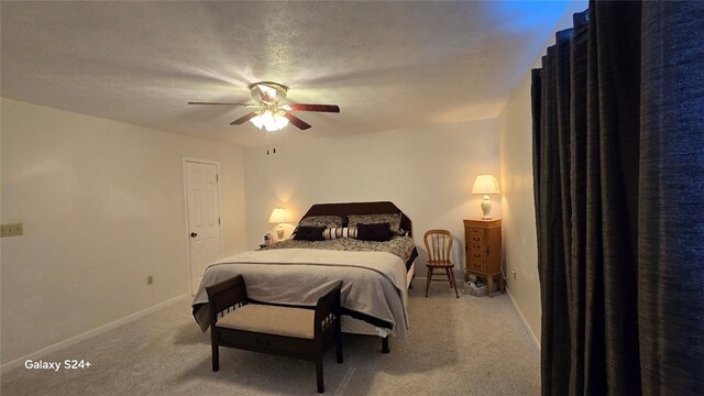 carpeted bedroom featuring ceiling fan and a textured ceiling