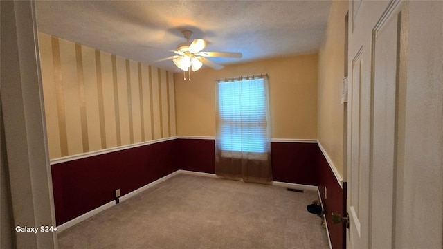 carpeted empty room with ceiling fan and a textured ceiling