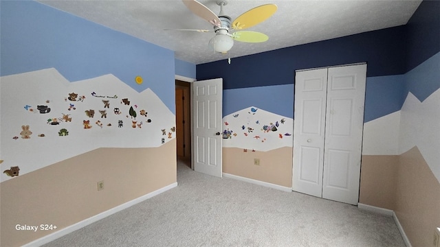 unfurnished bedroom featuring light colored carpet, a textured ceiling, ceiling fan, and a closet