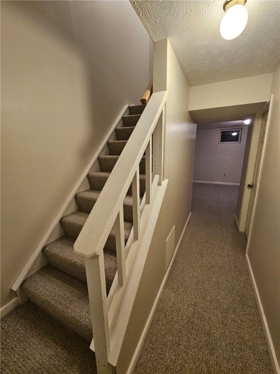 stairway featuring carpet floors and a textured ceiling