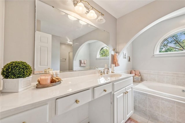 bathroom featuring tile patterned flooring, vanity, and a relaxing tiled tub