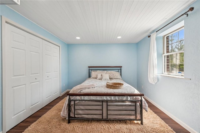 bedroom featuring dark hardwood / wood-style flooring, wooden ceiling, and a closet