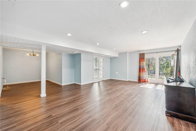 unfurnished living room with french doors, an inviting chandelier, wood ceiling, and wood-type flooring