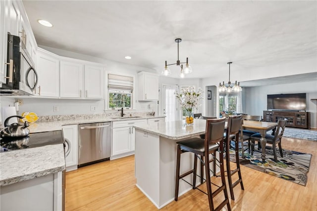 kitchen featuring sink, a center island, pendant lighting, white cabinets, and appliances with stainless steel finishes