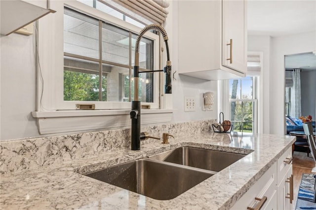 kitchen with sink, white cabinetry, and light stone counters