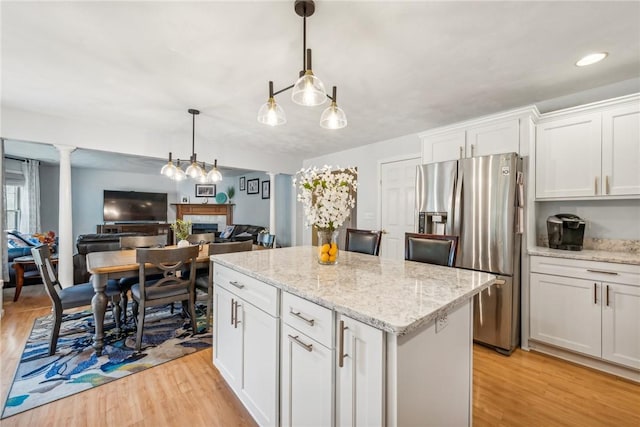 kitchen with a center island, stainless steel fridge with ice dispenser, decorative light fixtures, white cabinets, and light wood-type flooring