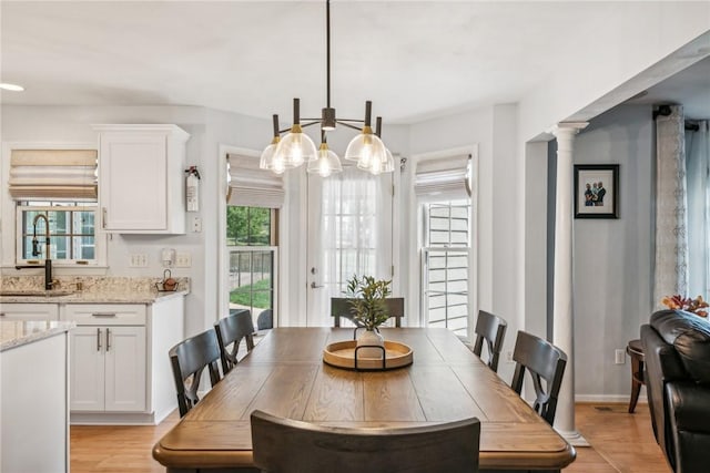 dining room featuring light wood-type flooring, decorative columns, and sink