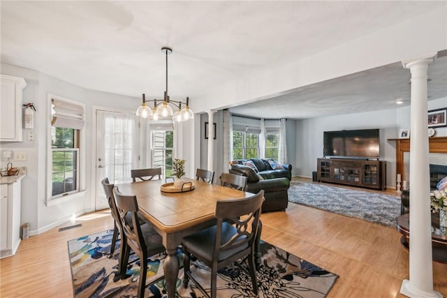 dining room with a fireplace, light hardwood / wood-style flooring, and an inviting chandelier