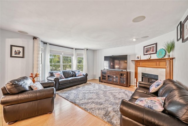 living room with light hardwood / wood-style flooring and a tiled fireplace