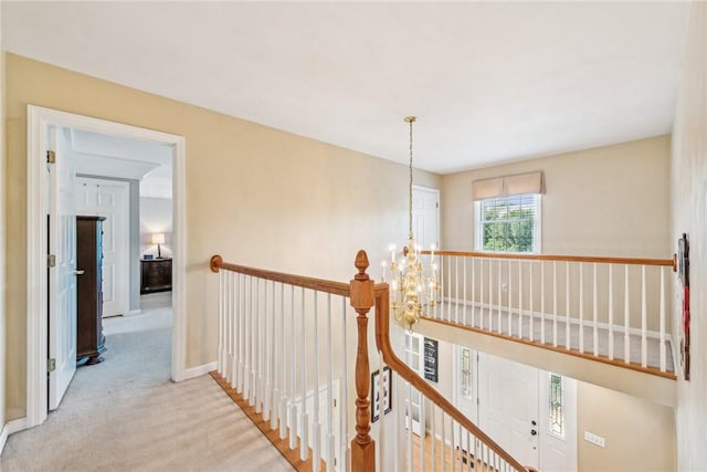 hallway with a chandelier and light colored carpet