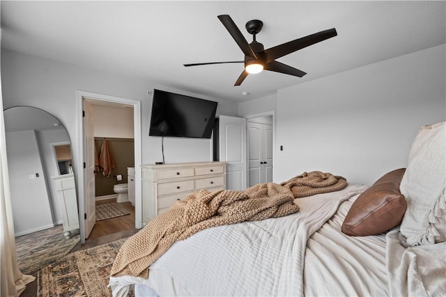 bedroom with ensuite bathroom, ceiling fan, wood-type flooring, a spacious closet, and a closet