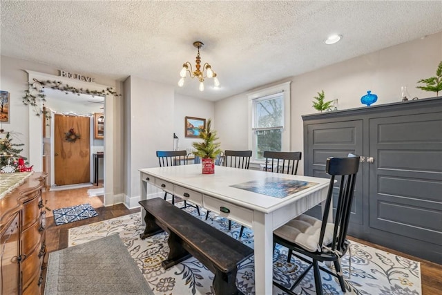 dining space featuring a notable chandelier, a textured ceiling, and dark wood-type flooring