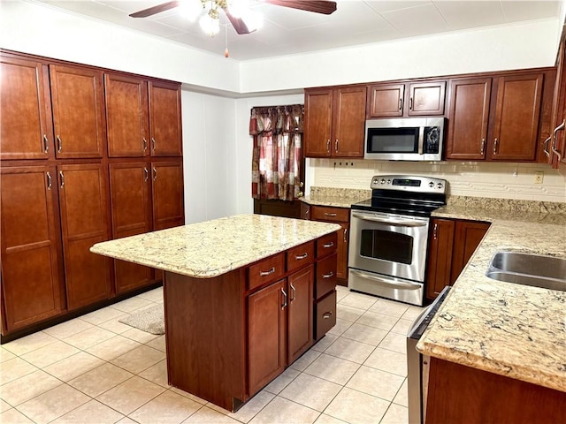 kitchen with light stone counters, a center island, light tile patterned flooring, and appliances with stainless steel finishes