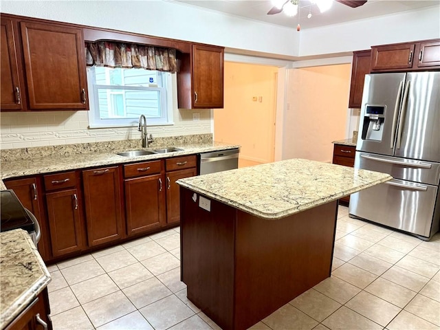 kitchen with a center island, sink, ceiling fan, light stone counters, and stainless steel appliances