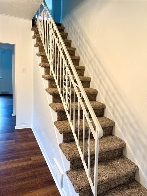 stairs with hardwood / wood-style flooring and wooden walls