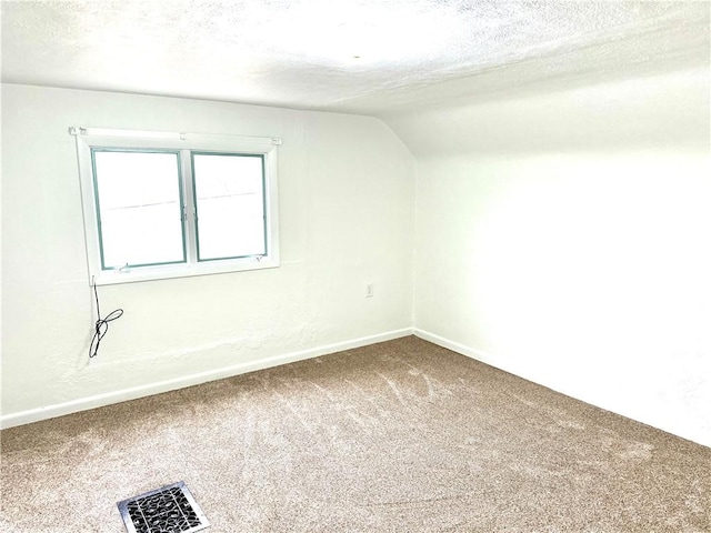 carpeted spare room with a textured ceiling and vaulted ceiling