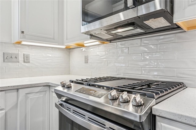 kitchen featuring white cabinets, appliances with stainless steel finishes, tasteful backsplash, and light stone countertops