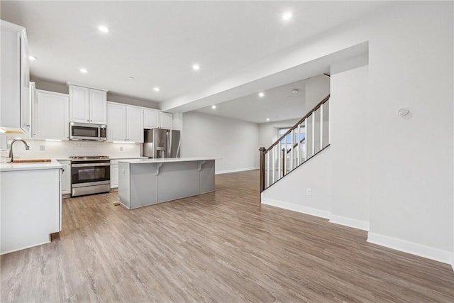 kitchen featuring white cabinetry, sink, a center island, stainless steel appliances, and light hardwood / wood-style floors