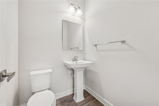 bathroom with wood-type flooring, toilet, and sink