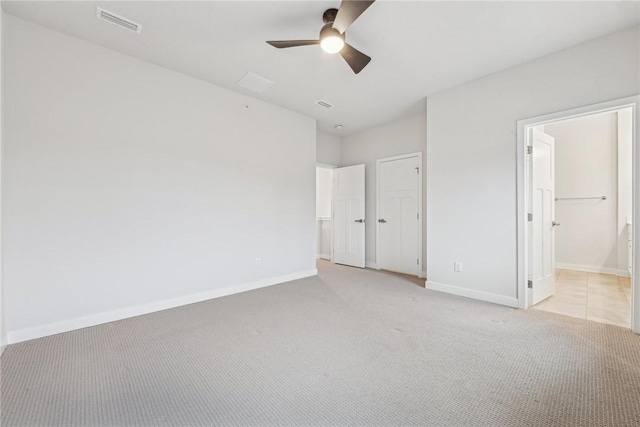 unfurnished bedroom with ensuite bath, ceiling fan, a closet, and light carpet