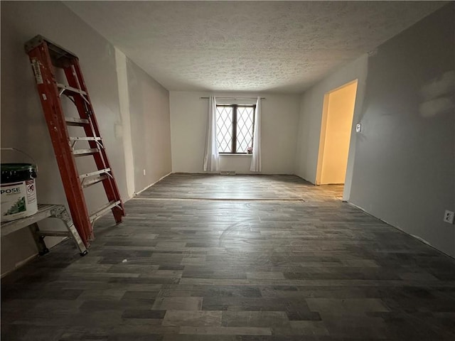 empty room with a textured ceiling and dark wood-type flooring