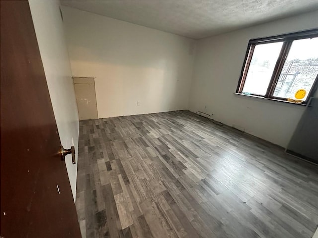 unfurnished room with a textured ceiling and hardwood / wood-style flooring