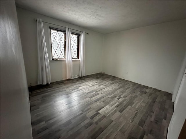 spare room featuring a textured ceiling and dark hardwood / wood-style floors