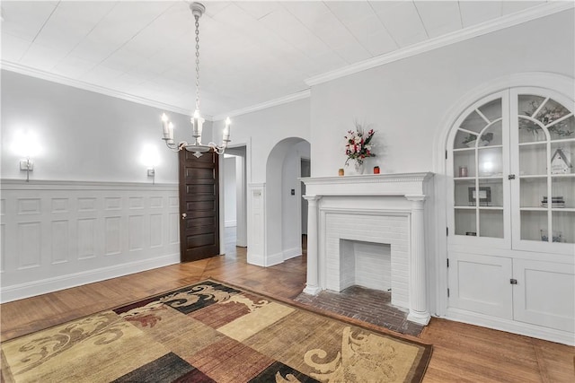 living room with a notable chandelier, dark hardwood / wood-style flooring, ornamental molding, and a brick fireplace