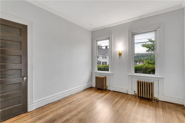 spare room featuring light wood-type flooring, ornamental molding, and radiator