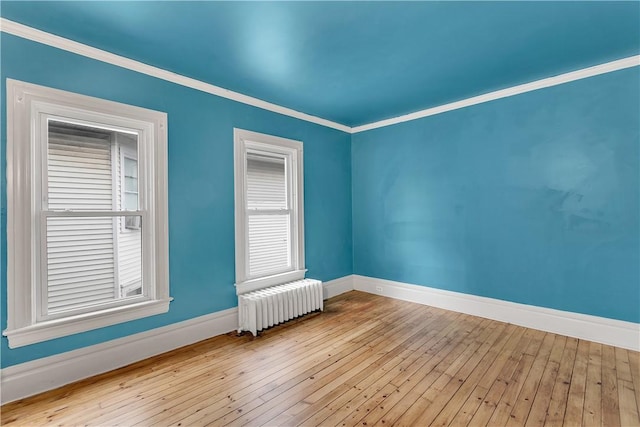 spare room featuring light hardwood / wood-style flooring, radiator, and crown molding