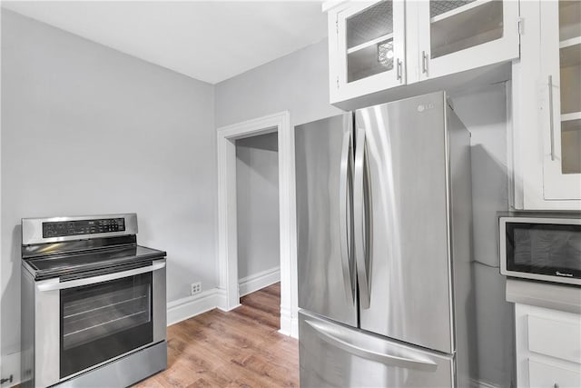 kitchen featuring hardwood / wood-style floors, white cabinetry, and appliances with stainless steel finishes