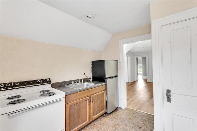 kitchen featuring white electric range oven, stainless steel fridge, vaulted ceiling, and sink