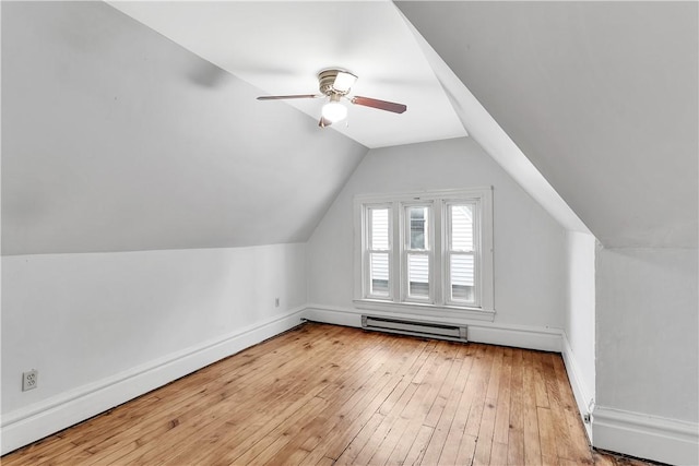 additional living space featuring lofted ceiling, light hardwood / wood-style floors, ceiling fan, and a baseboard heating unit