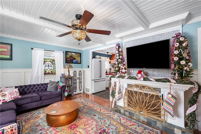 living room with beamed ceiling, ceiling fan, wood-type flooring, and ornamental molding