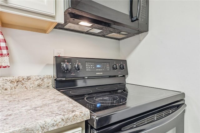 kitchen with black range with electric stovetop and white cabinetry