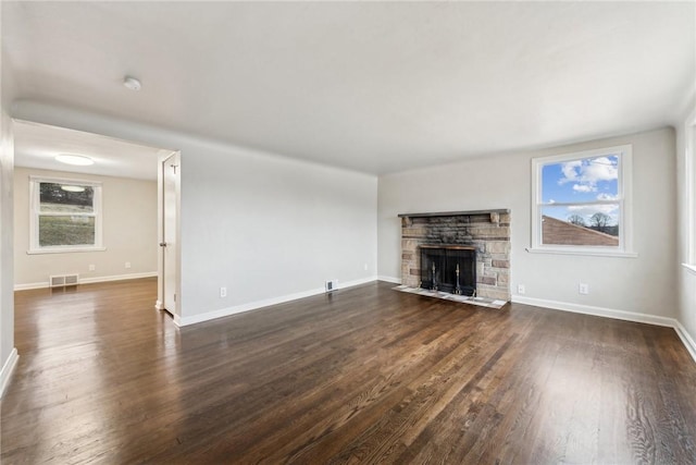 unfurnished living room with a fireplace, dark hardwood / wood-style flooring, and a wealth of natural light