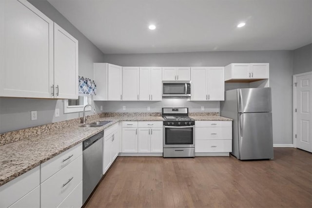 kitchen featuring light stone countertops, appliances with stainless steel finishes, dark wood-type flooring, sink, and white cabinets