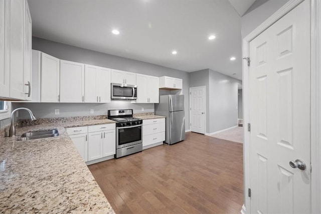 kitchen featuring light stone countertops, light hardwood / wood-style flooring, white cabinets, and appliances with stainless steel finishes