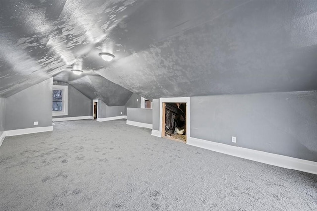 additional living space with carpet, a fireplace, and vaulted ceiling