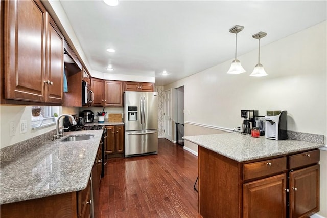 kitchen with decorative light fixtures, sink, light stone countertops, and stainless steel appliances