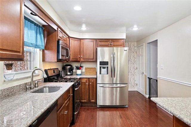 kitchen with light stone countertops, sink, dark wood-type flooring, and appliances with stainless steel finishes