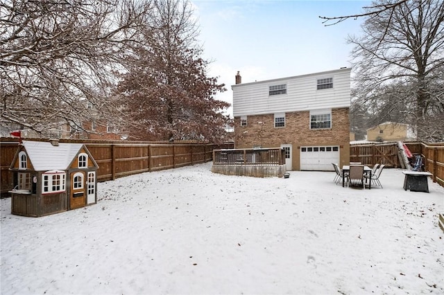 snow covered back of property with a deck