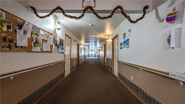 corridor with dark carpet and a textured ceiling