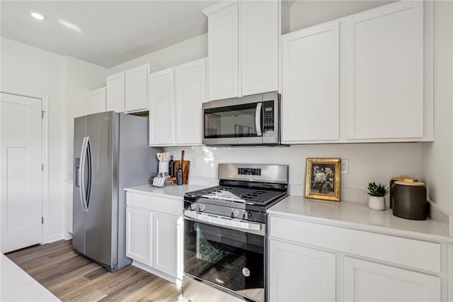 kitchen with white cabinetry, stainless steel appliances, and light hardwood / wood-style floors