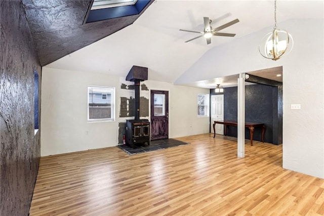 unfurnished living room featuring lofted ceiling, light hardwood / wood-style floors, and a wood stove