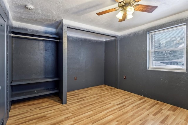 unfurnished bedroom featuring hardwood / wood-style flooring, ceiling fan, and a textured ceiling