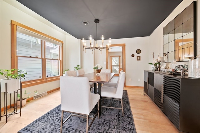 dining area with light wood-type flooring and an inviting chandelier