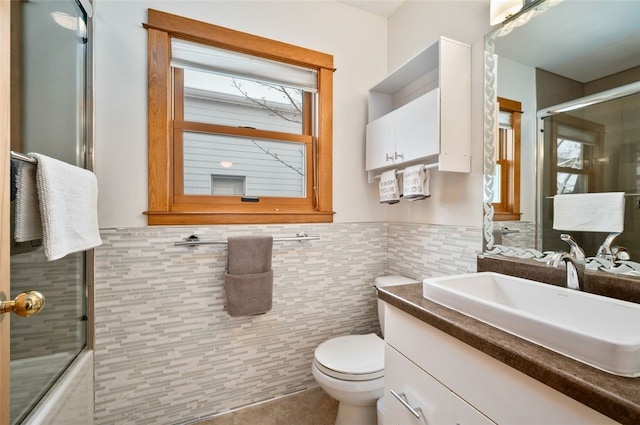 bathroom featuring vanity, toilet, walk in shower, and tile walls